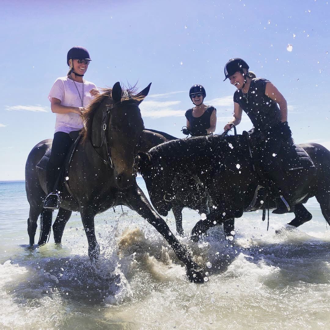 Riders cantering through the shallows on a beach ride, Jesters Flat