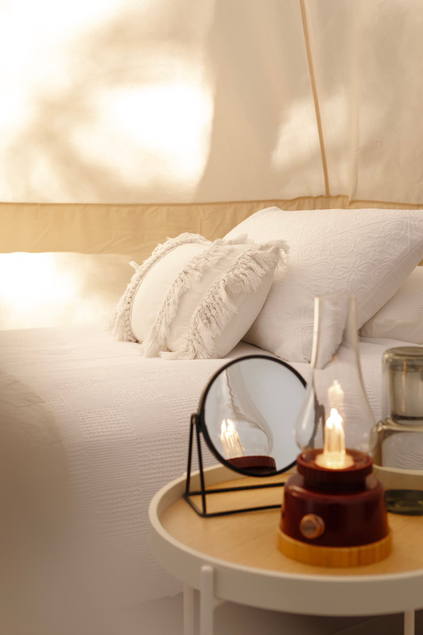 Bell-tent bed made up in soft linen at golden hour, Jesters Flat